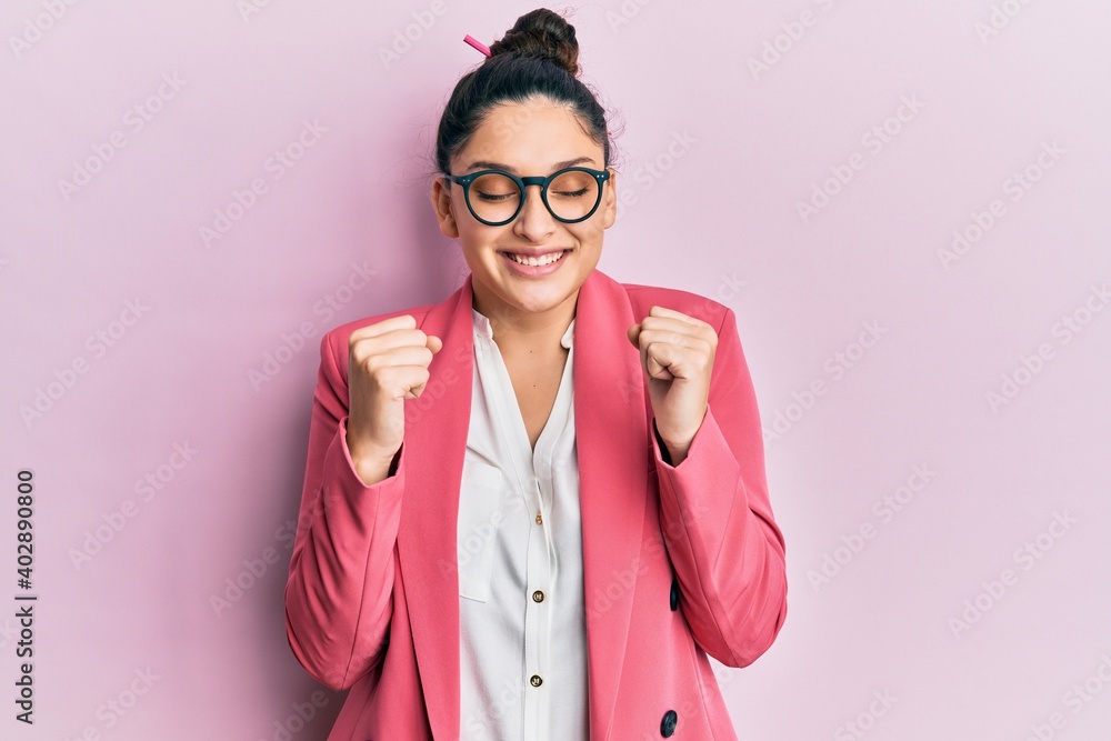Beautiful middle eastern woman wearing business jacket and glasses excited for success with arms raised and eyes closed celebrating victory smiling. winner concept.