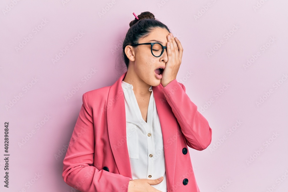 Beautiful middle eastern woman wearing business jacket and glasses yawning tired covering half face, eye and mouth with hand. face hurts in pain.