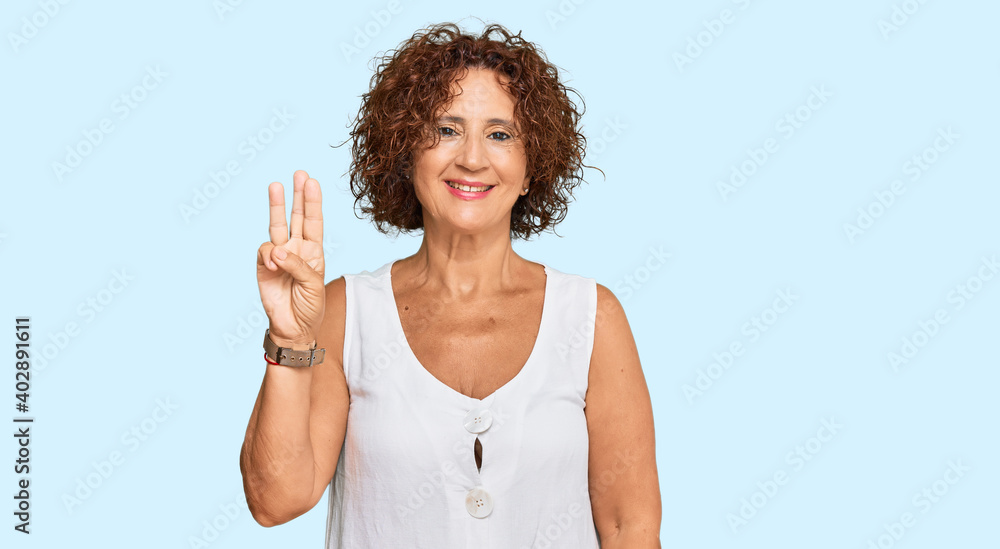 Beautiful middle age mature woman wearing casual white shirt showing and pointing up with fingers number three while smiling confident and happy. Beautiful middle age mature woman wearing casual white shirt showing and pointing up with fingers number three while smiling confident and happy.