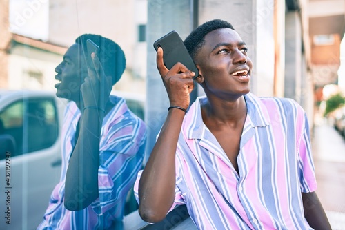 Young african american man smiling happy tallking on the smartphone at street of city. photo