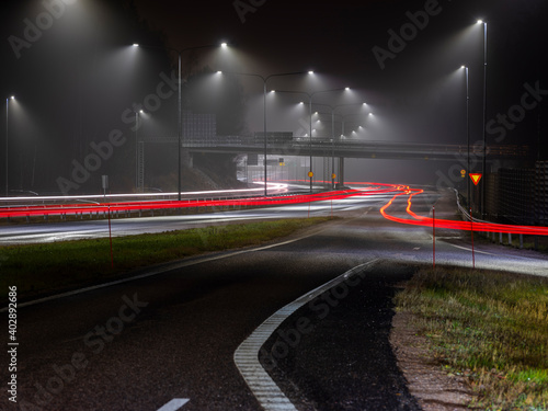 Streetlights casting reflection on a fuggy evening. Light trails on the highway.