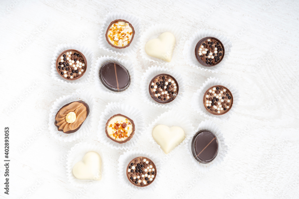 Different chocolate pralines. Belgian pralines of different shapes in paper baskets. Assortment of fine belgium white, dark and milk chocolates isolated on a white background Different chocolate pralines. Belgian pralines of different shapes in paper baskets. Assortment of fine belgium white, dark and milk chocolates isolated on a white background