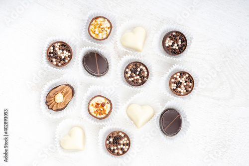 Different chocolate pralines. Belgian pralines of different shapes in paper baskets. Assortment of fine belgium white, dark and milk chocolates isolated on a white background