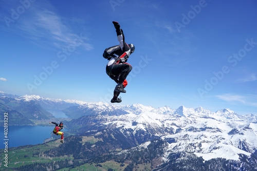 Skydivers perform tricks above snowcapped mountains