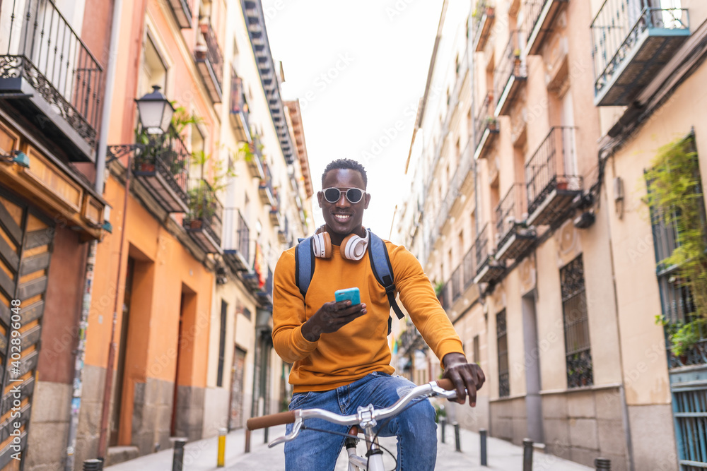Black Man Riding Bike Using Cellphone Outdoors. Black Man Riding Bike Using Cellphone Outdoors.