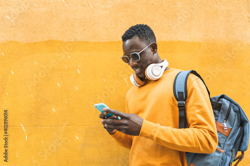 Black Man Using Cellphone Wearing Yellow Sweater Outdoors.