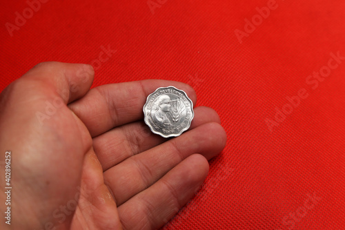 Old coin from India in hand on red background