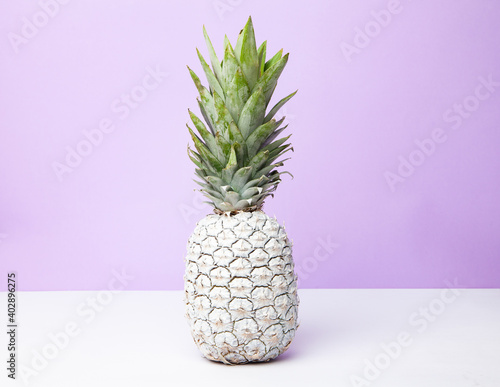 White pineapple on table in studio on violet background