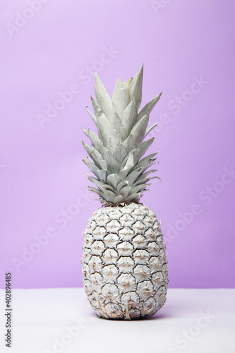 White pineapple on table in studio on violet background