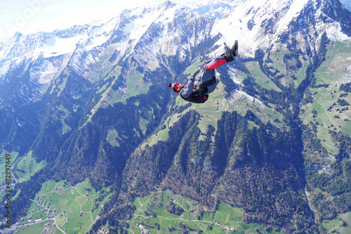 Parasailor freefalls above snowcapped mountains