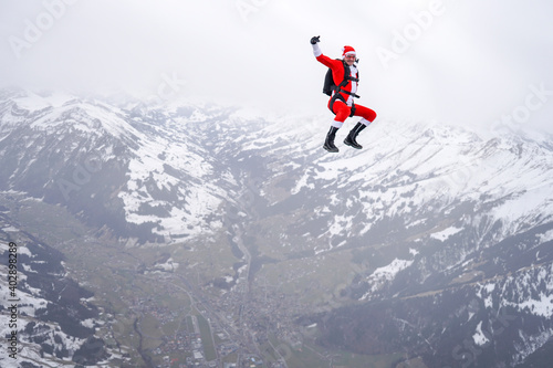 Skydiver dressed in Santa Claus outfit flies above snowcapped mountains