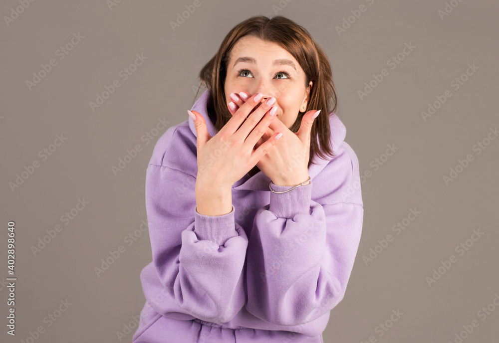 Happy woman closing her mouth with hands going to see surprise prepared by husband standing and smiling in anticipation for something wonderful. Young cheerful lady covering face with hand Happy woman closing her mouth with hands going to see surprise prepared by husband standing and smiling in anticipation for something wonderful. Young cheerful lady covering face with hand