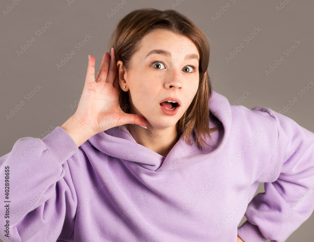 Gossip woman hearing with hand on ear isolated on a gray background Gossip woman hearing with hand on ear isolated on a gray background