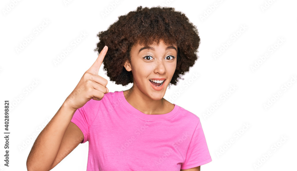 Young hispanic girl wearing casual clothes pointing finger up with successful idea. exited and happy. number one.