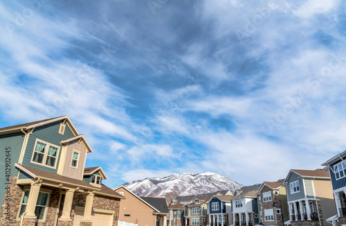 Houses facade with snowy mountain peak and cloudy blue sky on a winter landscape