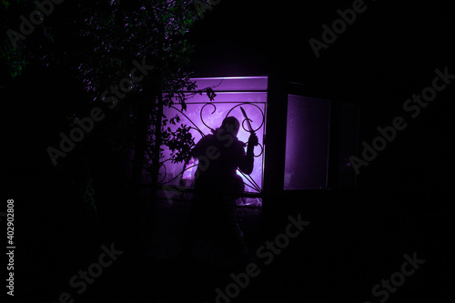 Silhouette of an unknown shadow figure on a door through a closed glass door. The silhouette of a human in front of a window at night. © zef art