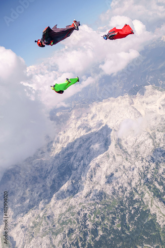 Tandem wingsuit fliers glide over mountains at sunrise