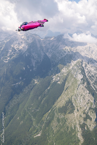 Wingsuit flier glides over mountains at sunrise
