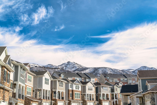 Beautiful houses in Utah Valley against snowy mountain peak and cloudy blue sky