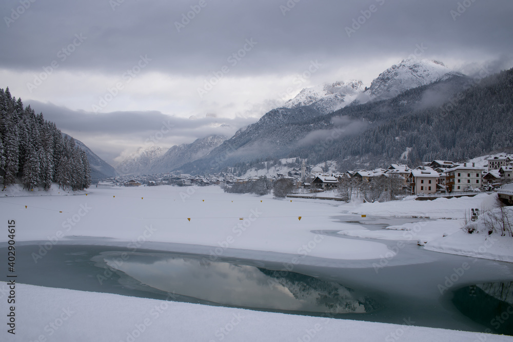 Fototapeta premium le nuvole sulla montagna in inverno, la luce che filtra le nuvole attorno una montagna innevata, lo splendido panorama invernale sulle dolomiti