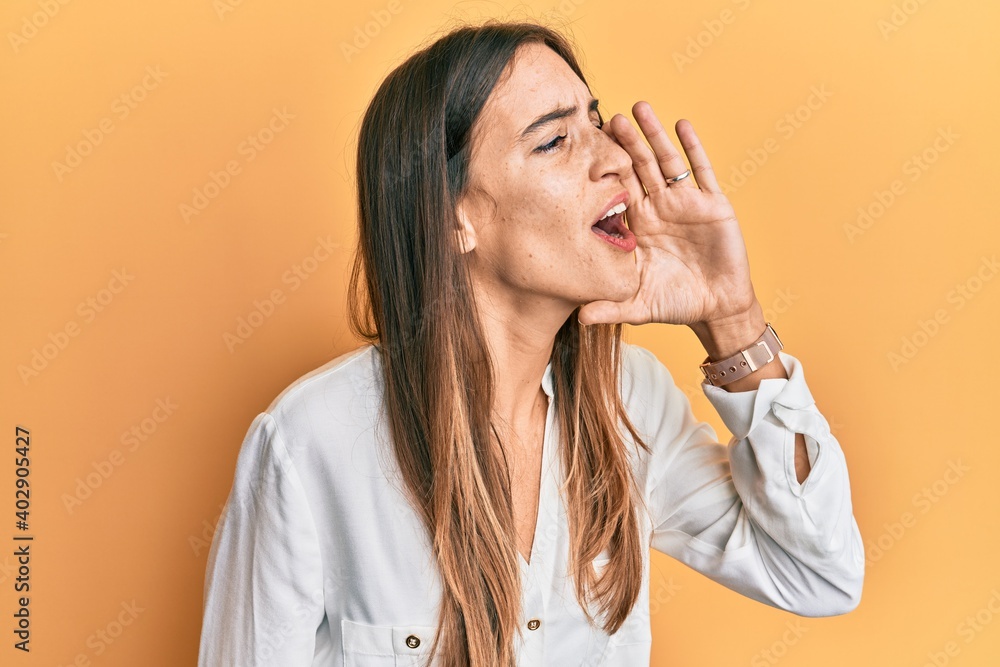 Young beautiful woman wearing casual clothes shouting and screaming loud to side with hand on mouth. communication concept. Young beautiful woman wearing casual clothes shouting and screaming loud to side with hand on mouth. communication concept.