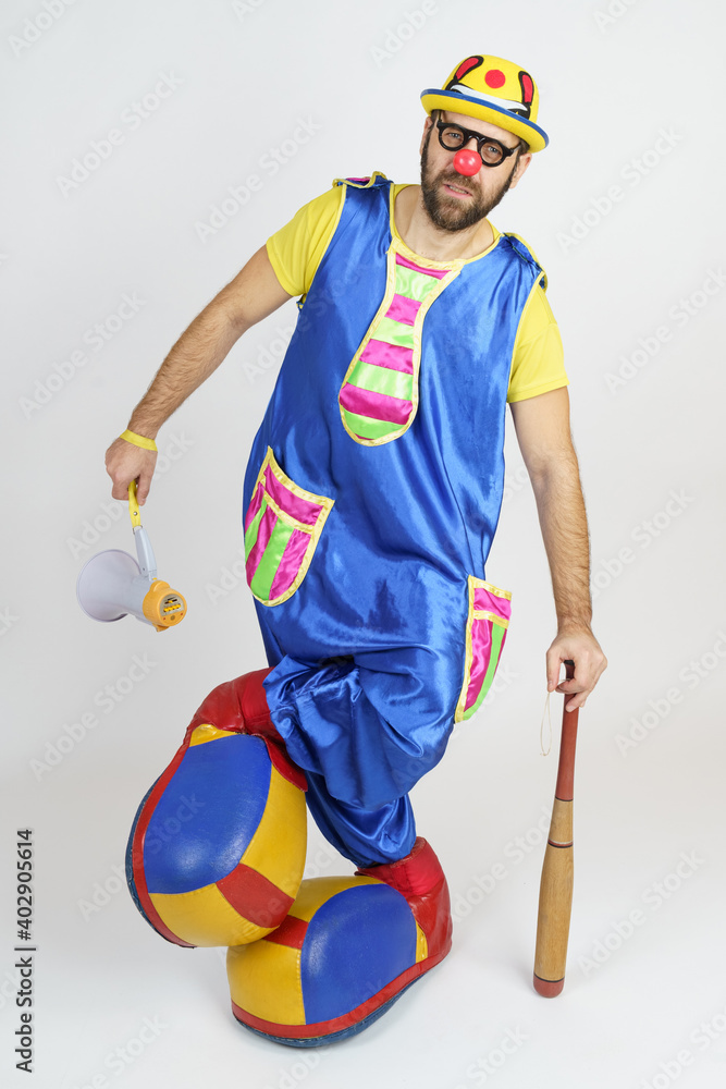 The clown is a man in a bright blue and yellow suit with a baseball bat and a loudspeaker. The clown is a man in a bright blue and yellow suit with a baseball bat and a loudspeaker.