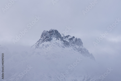 le nuvole sulla montagna in inverno, la luce che filtra le nuvole attorno una montagna innevata, lo splendido panorama invernale sulle dolomiti © giovanni