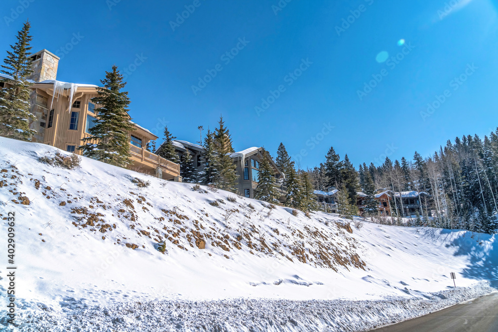 Posh houses on snow covered mountain terrain in winter with view of paved road