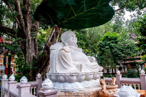 Statue of a fat and smiling Buddha in a Vietnamese pagoda. photo