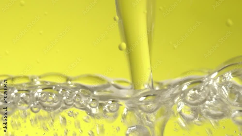 Yellow Soda pouring down into clear glass standing on yellow background in slowmotion Yellow Soda pouring down into clear glass standing on yellow background in slowmotion