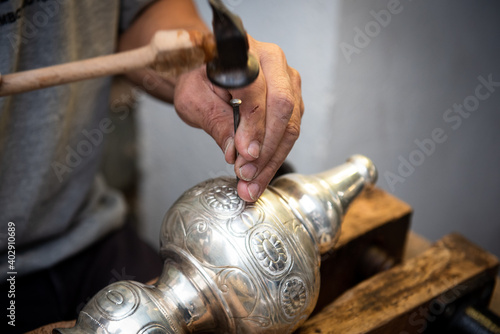 Jewellery maker working in workshop crafting homemade silver vase. photo