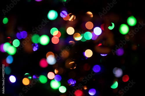 Abstract blurred background with numerous colourful bright festive bokeh on Christmas tree. Texture with copy space. Celebration, holidays, New Year concept. Horizontal