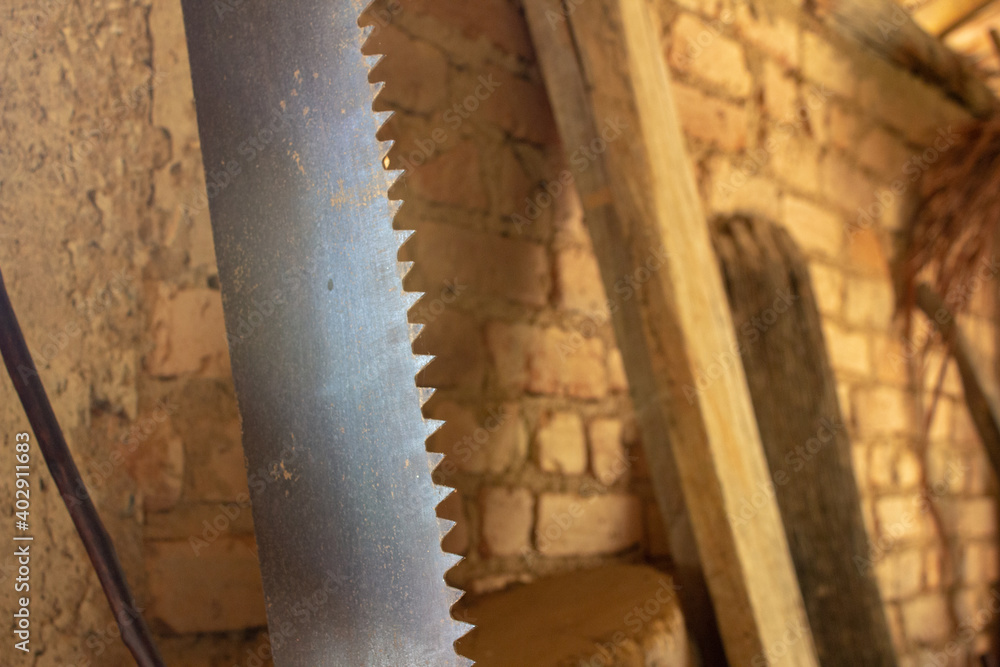 Old hand saw resting on a brick wall of a farm Old hand saw resting on a brick wall of a farm
