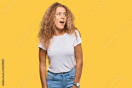 Beautiful caucasian teenager girl wearing casual white tshirt angry and mad screaming frustrated and furious, shouting with anger. rage and aggressive concept.