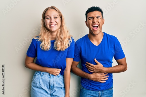 Young interracial couple wearing casual clothes smiling and laughing hard out loud because funny crazy joke with hands on body. © Krakenimages.com