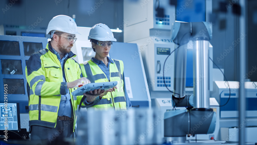 Factory Workshop: Professional Female Engineer, Male Machinery Operator Use Industrial Digital Tablet Computer to Work and Program Robot Arm for Production Line. High-Tech Facility with CNC Machines Factory Workshop: Professional Female Engineer, Male Machinery Operator Use Industrial Digital Tablet Computer to Work and Program Robot Arm for Production Line. High-Tech Facility with CNC Machines