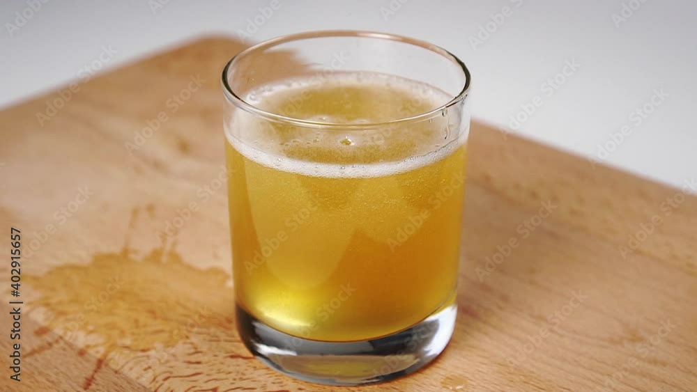 Full glass of apple cider with foam and bubbles on a cutting board. Full glass of apple cider with foam and bubbles on a cutting board.