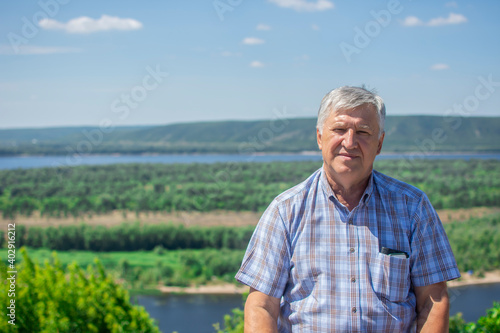 Portrait of a handsome senior man with a beautiful river landscape on the background. Happy old man relaxing outdoor.  © Ersin