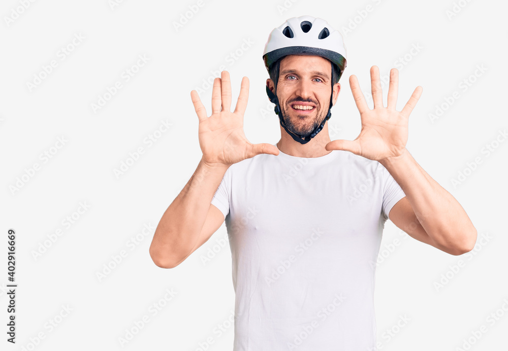 Young handsome man wearing bike helmet showing and pointing up with fingers number ten while smiling confident and happy. Young handsome man wearing bike helmet showing and pointing up with fingers number ten while smiling confident and happy.