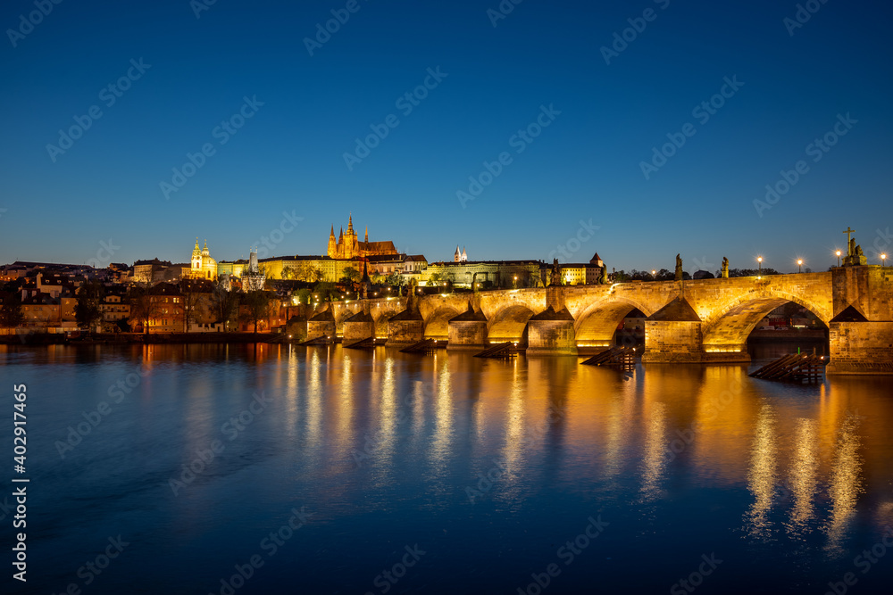 View on Charles Bridge and Prague Castle over Vltava River during early night with wonderful blue sky and yellow city lights, Czechia, Europe View on Charles Bridge and Prague Castle over Vltava River during early night with wonderful blue sky and yellow city lights, Czechia, Europe