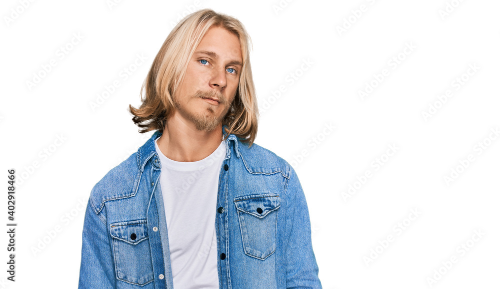 Caucasian man with blond long hair wearing casual denim jacket looking sleepy and tired, exhausted for fatigue and hangover, lazy eyes in the morning. Caucasian man with blond long hair wearing casual denim jacket looking sleepy and tired, exhausted for fatigue and hangover, lazy eyes in the morning.