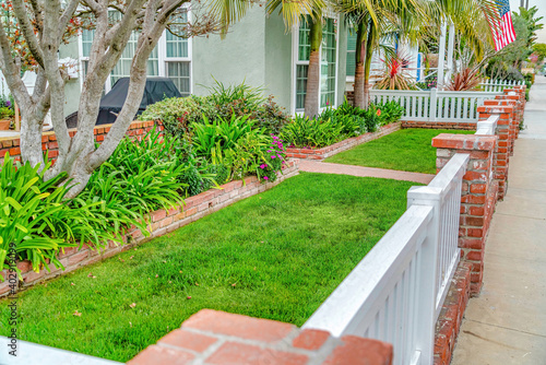 Front yard of home with green lawn pathway wooden fence and red brick posts photo