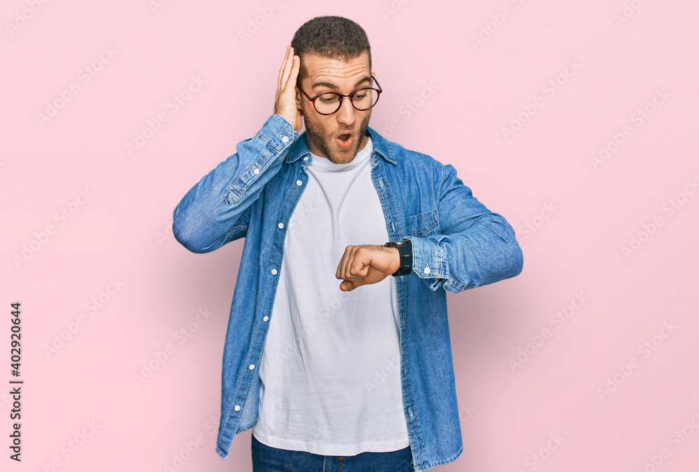 Young caucasian man wearing casual clothes looking at the watch time worried, afraid of getting late Young caucasian man wearing casual clothes looking at the watch time worried, afraid of getting late