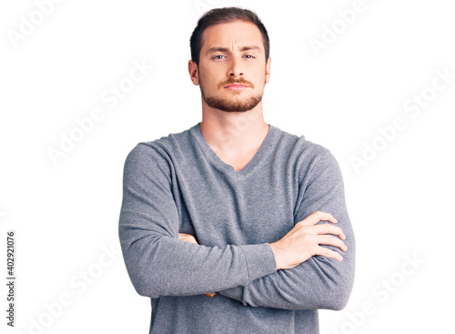 Young handsome caucasian man wearing casual winter sweater skeptic and nervous, disapproving expression on face with crossed arms. negative person.