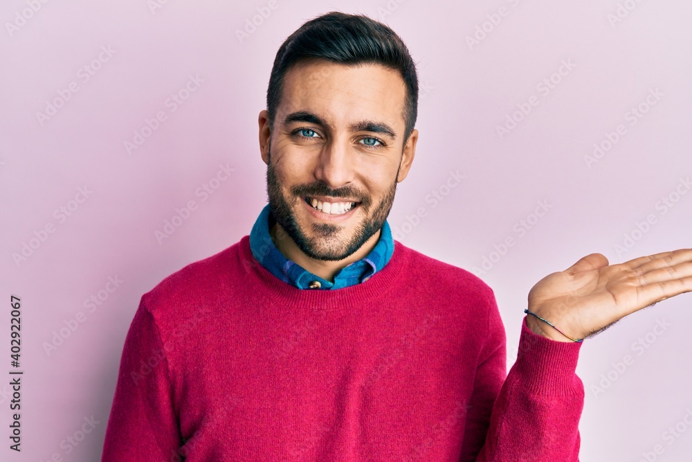 Young hispanic man wearing casual clothes smiling cheerful presenting and pointing with palm of hand looking at the camera. Young hispanic man wearing casual clothes smiling cheerful presenting and pointing with palm of hand looking at the camera.