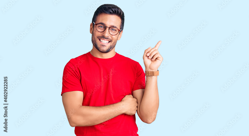 Fototapeta premium Young hispanic man wearing casual clothes and glasses smiling happy pointing with hand and finger to the side