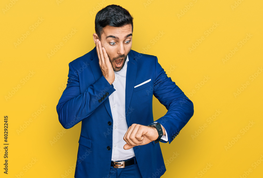 Young hispanic man wearing business jacket looking at the watch time worried, afraid of getting late Young hispanic man wearing business jacket looking at the watch time worried, afraid of getting late