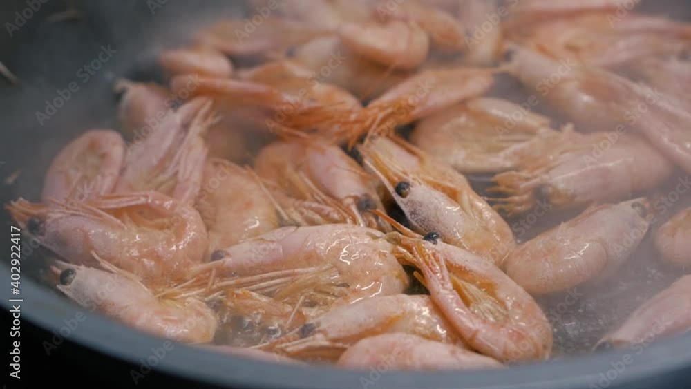 Frying shrimps in a pan with oil and spices slow motion