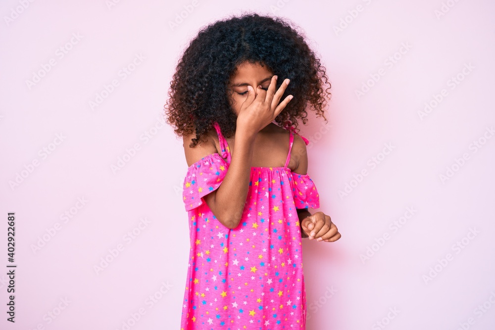 African american child with curly hair wearing casual dress tired rubbing nose and eyes feeling fatigue and headache. stress and frustration concept. African american child with curly hair wearing casual dress tired rubbing nose and eyes feeling fatigue and headache. stress and frustration concept.