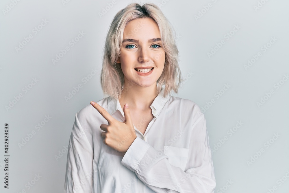 Young blonde girl wearing casual clothes smiling cheerful pointing with hand and finger up to the side Young blonde girl wearing casual clothes smiling cheerful pointing with hand and finger up to the side